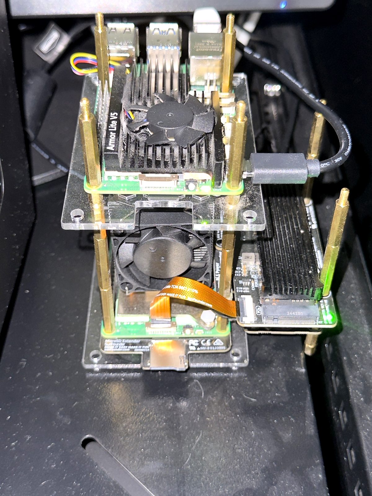 Two Raspberry Pi 5 boards stacked in an open acrylic cluster case with heatsinks, fans, and an NVMe HAT